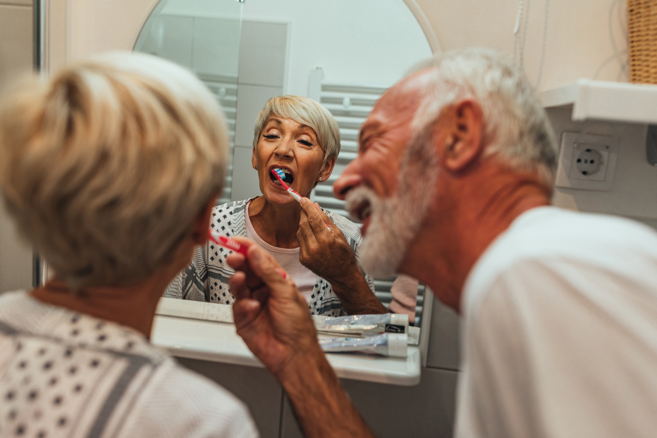 Elderly man brushing wife’s teeth