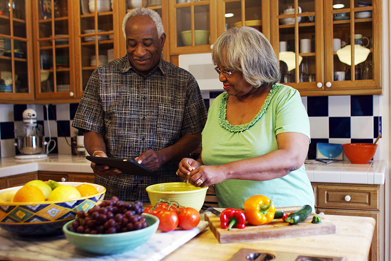 Older adult couple preparing healthy food together in the kitchen.