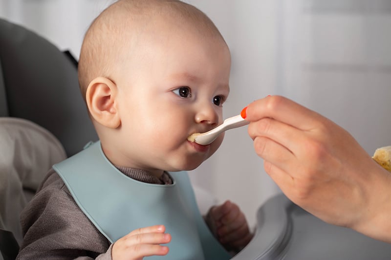 Baby being spoon-fed solid foods.