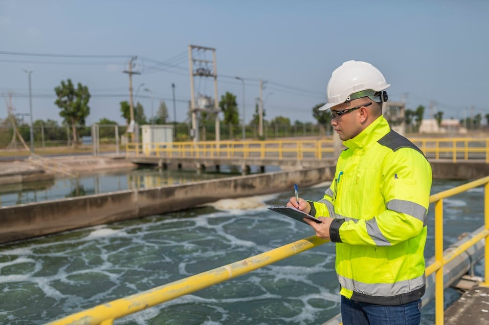 Environmental engineer taking notes at a wastewater treatment plant. 