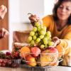 Woman choosing grapes from a basket of fruit Woman choosing grapes from a basket of fruit
