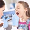 Woman doctor examining a girls throat with a spatula and flashlight Woman doctor examining a girls throat with a spatula and flashlight