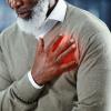 Man with his hand over his heart in pain Man with his hand over his heart in pain