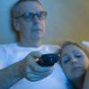 Sleepy couple watching television in bed Sleepy couple watching television in bed