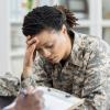 Female military veteran holding her head in an appointment with a health care professional Female military veteran holding her head in an appointment with a health care professional