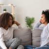 Mom listening to her teenage daughter while sitting on couch together Mom listening to her teenage daughter while sitting on couch together