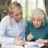 Woman helping an older adult with paperwork Woman helping an older adult with paperwork