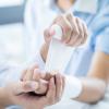 Close up of a doctor bandaging the upper limb on a patient Close up of a doctor bandaging the upper limb on a patient