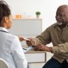 Health care provider handing older adult patient a pack of pills