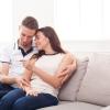 Young couple looking at a pregnancy test on the couch