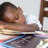 Boy asleep on his desk with his head on a book Boy asleep on his desk with his head on a book