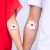 Blood donors showing their bandages with hearts on them, after blood donation Blood donors showing their bandages with hearts on them, after blood donation.