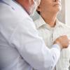 Doctor listening to an older patient's chest with a stethoscope Doctor listening to an older patient's chest with a stethoscope