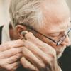 Older man placing a hearing aid in his ear Older man placing a hearing aid in his ear.