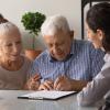 Older adult signing paperwork with his family.