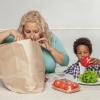Mom and son taking healthy groceries out of a paper shopping bag.