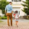 Father leading his daughter to school, holding her hand.