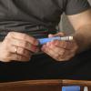 Man sitting on a couch preparing a GLP-1RA injection.