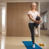 Older woman standing on one leg on a yoga mat while holding other leg.