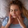 Girl holding her jaw and clenching her teeth while laying down.