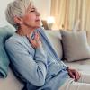 Older woman holding her hand over her chest in pain.