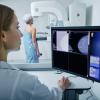 A technician looking at mammogram results on a computer.