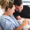 Parents holding a newborn in a hospital bed.