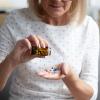 An older adult pouring medicine out of a bottle into her hands. 