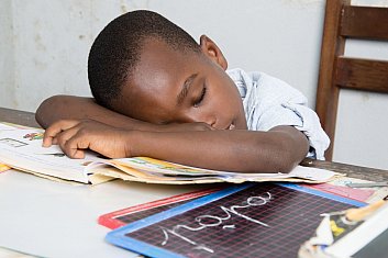 Boy asleep on his desk with his head on a book