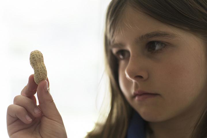 Girl looking skeptically at a peanut