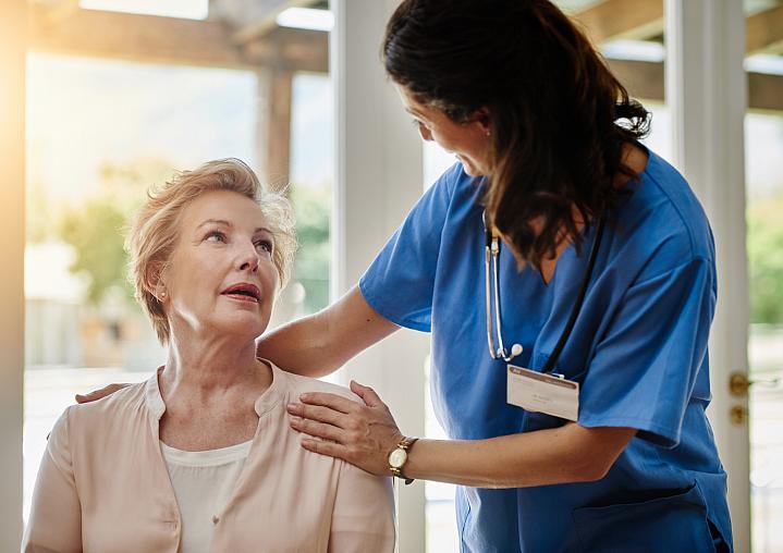 Health care provider smiling while talking to an older adult