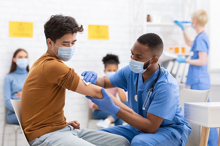 A young man getting a vaccination in a hospital setting
