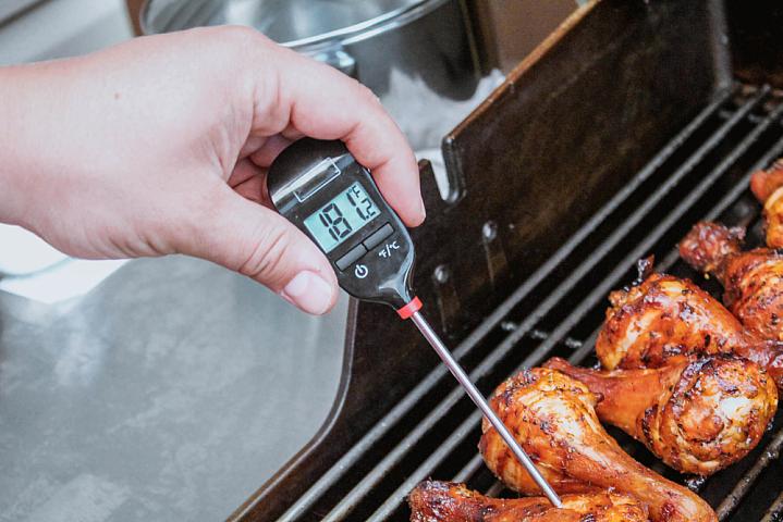 Thermometer showing temperature of chicken that’s being grilled