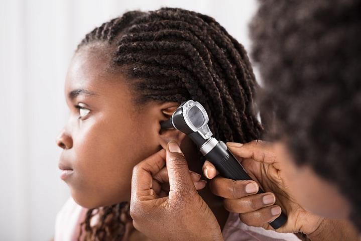 Young girl getting her ears checked by a health care provider