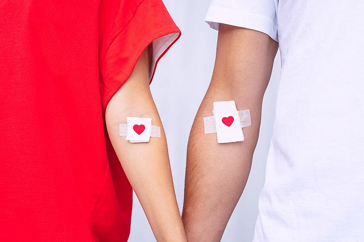 Blood donors showing their bandages with hearts on them, after blood donation.