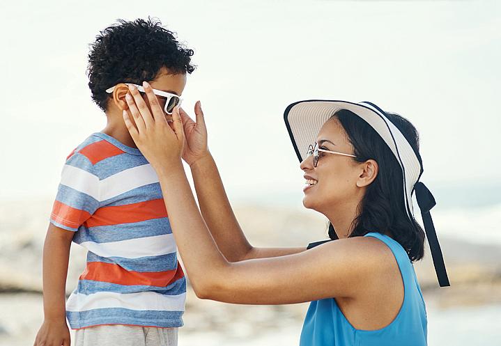 A mother putting sunglasses on her child.